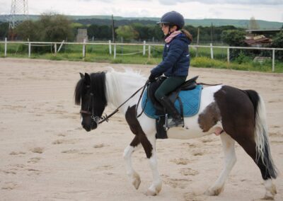 Niña aprendiendo a montar en poni